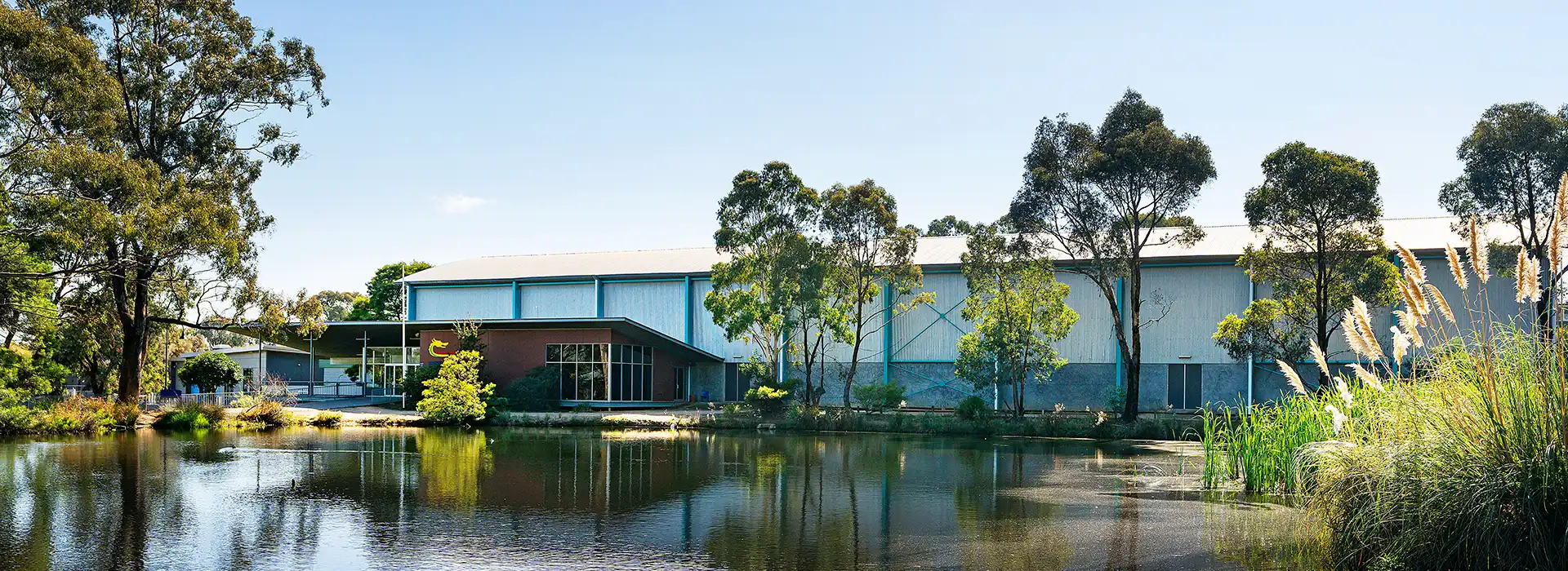 Exterior of Bendigo South East College Stadium showing sky and nearby lake